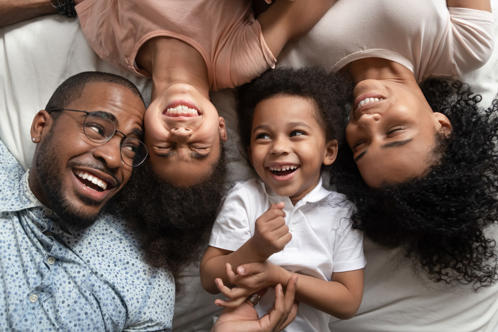 Happy family lying together on bed, laughing and smiling while enjoying joyful bonding time